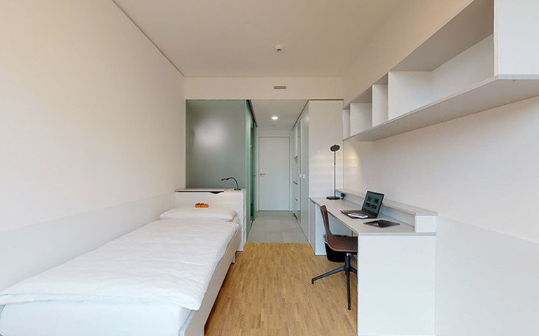 A cozy dorm room on the EHL with a bed, desk, and shelves